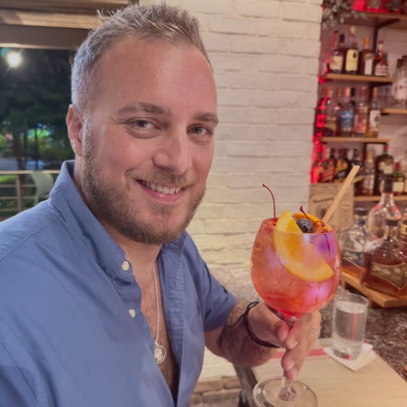 Robbie Parker at a bar in Playas del Coco, holding a cocktail and smiling at the camera